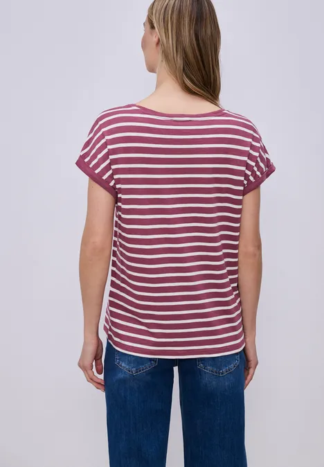 Eine Frau von hinten trägt ein rot-weiß gestreiftes T-Shirt und blaue Jeans.